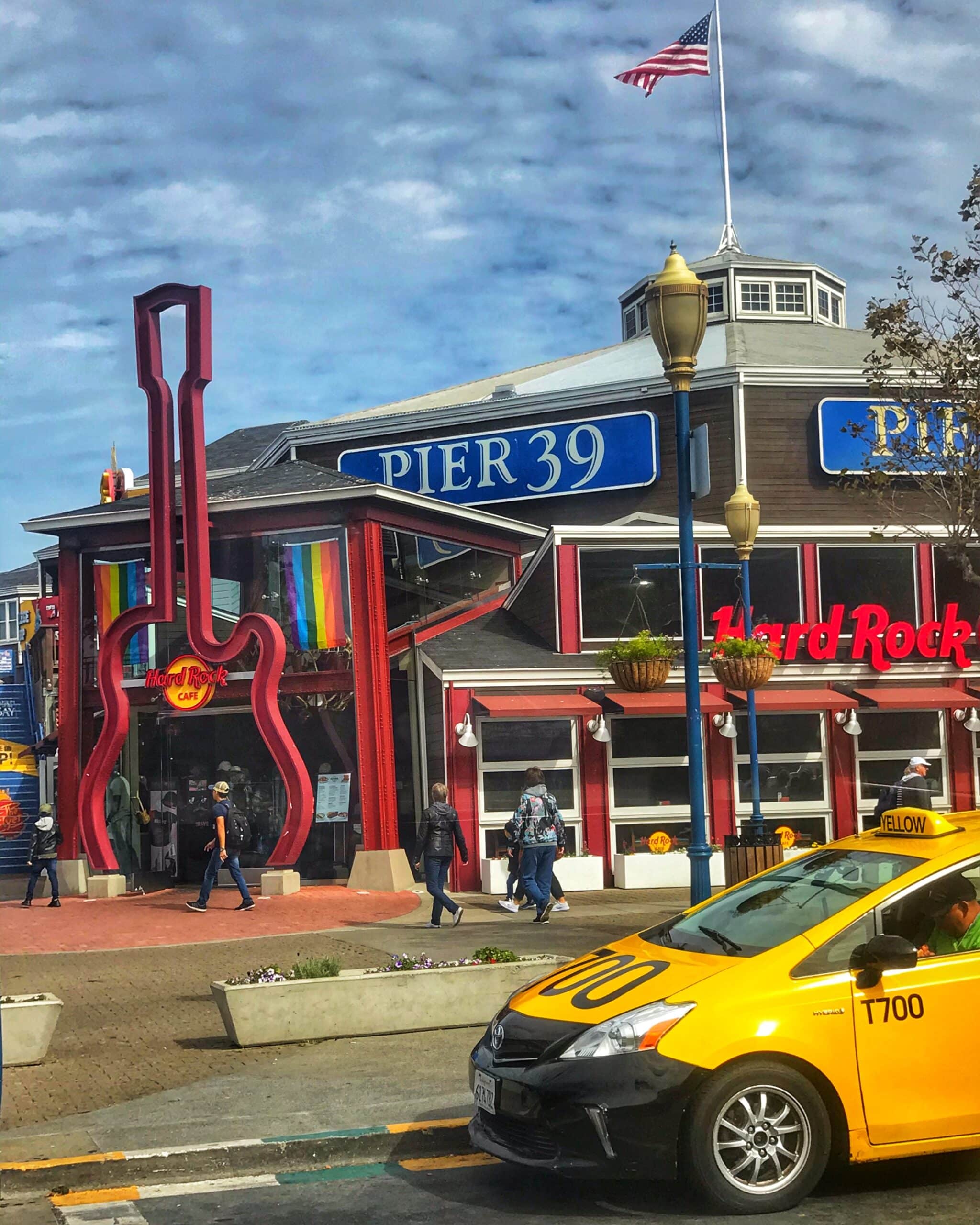 Fachada del Hard Rock café en Pierre 39 San Francisco con un taxi amarillo clásico frente al local, mostrando ambiente turístico y urbano de la ciudad
