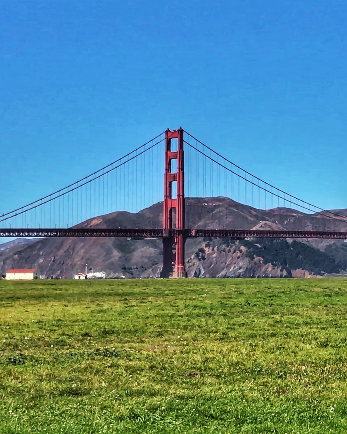 Vista del icónico puente rojo de San Francisco, conocido como el puente Golden Gate sobre la bahía con cielo, despejado y paisaje de fondo