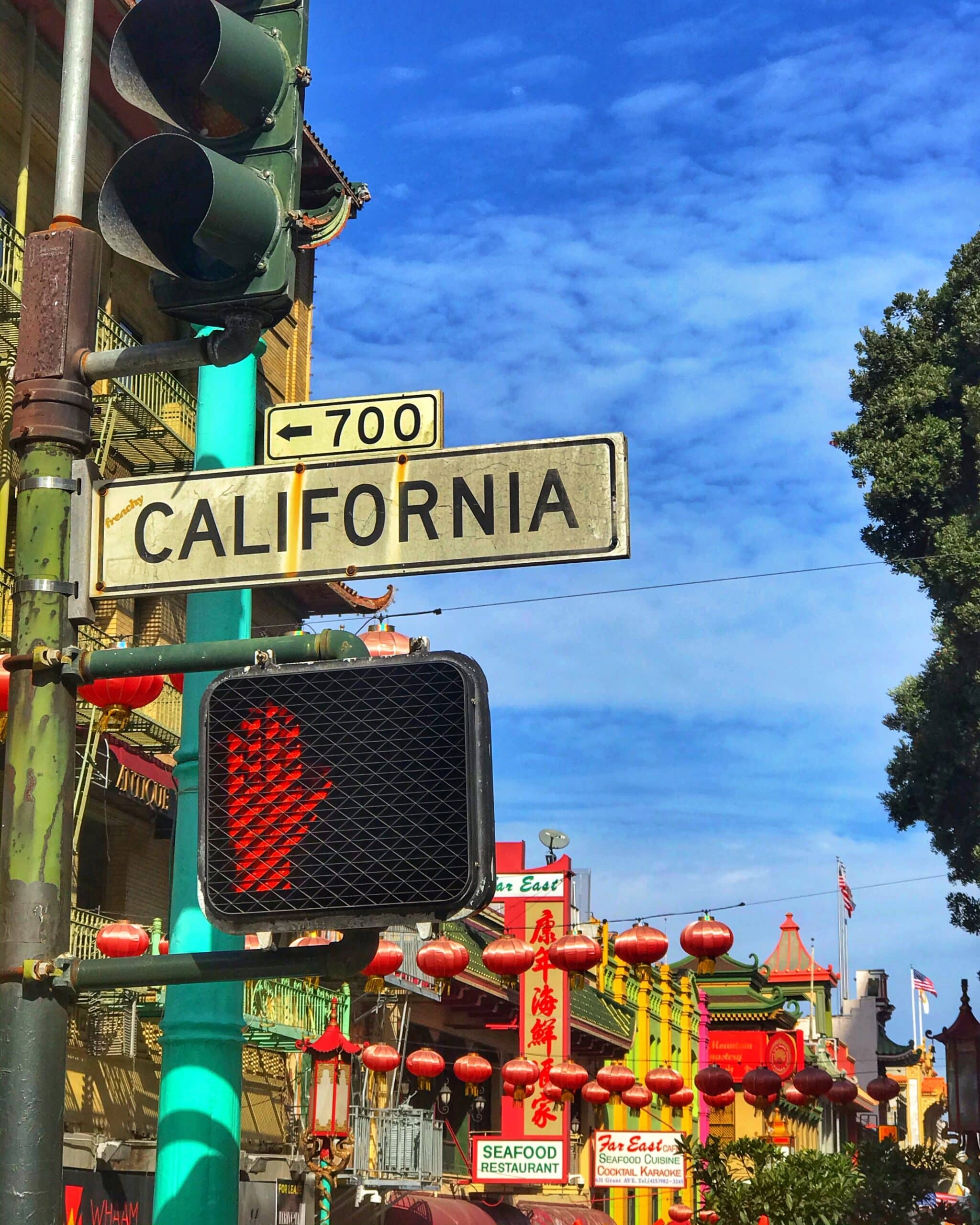 Semáforo en rojo y cartel que dice California en una calle de San Francisco con edificios del barrio chino al fondo, mostrando un típico paisaje urbano de la ciudad