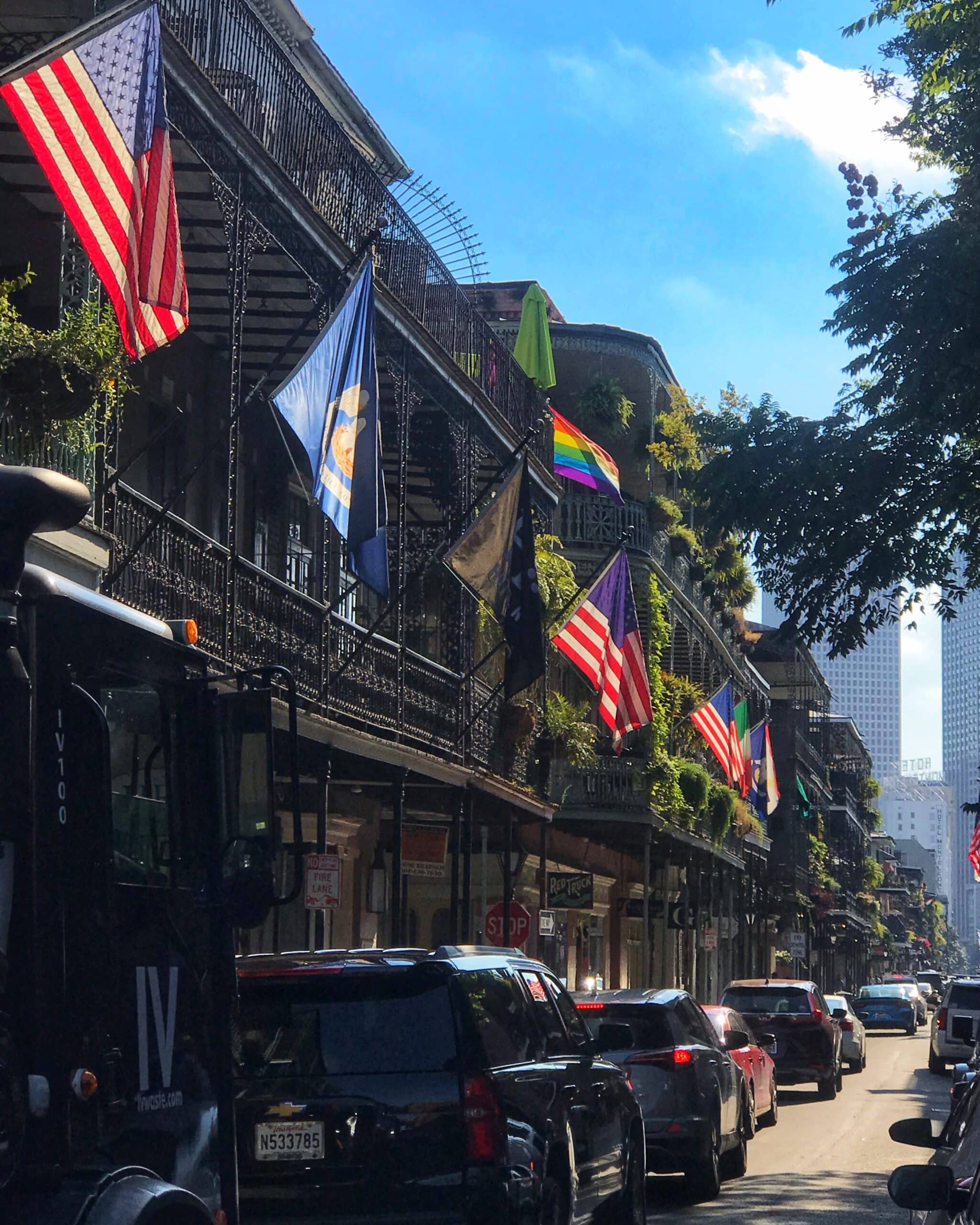 Edificios históricos de Nueva Orleans con banderas y coches en la calle, mostrando la arquitectura clásica y el encanto urbano de la ciudad