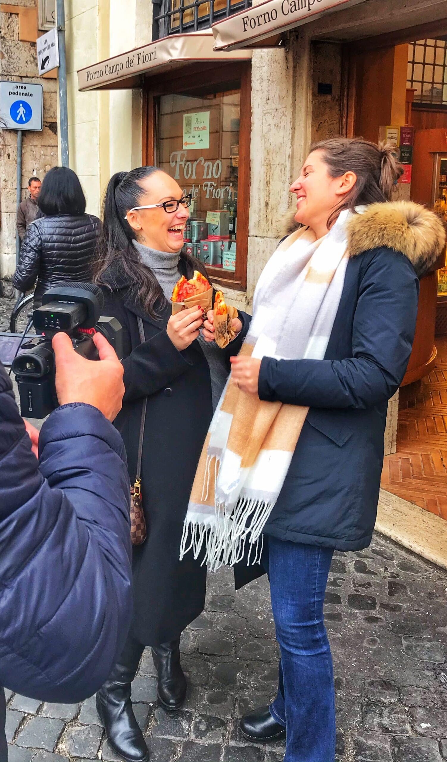 Dos chicas, siendo grabadas mientras prueban comida típica italiana en Roma para el programa mercados del mundo, mostrando platos tradicionales y ambiente culinario romano