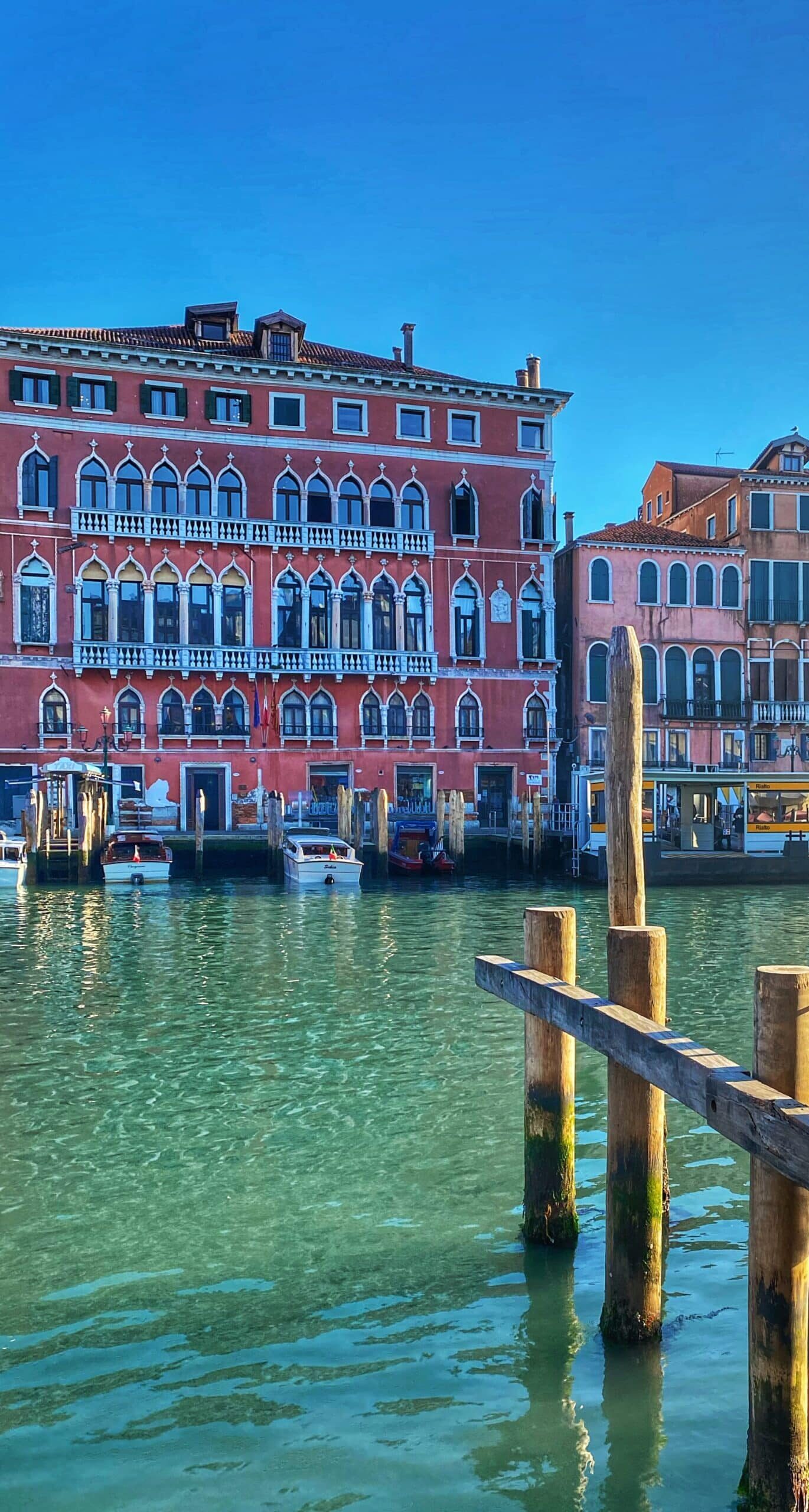 Vista de los edificios históricos a orillas del canal de Venecia, con reflejos en el agua y la típica atmósfera veneciana.