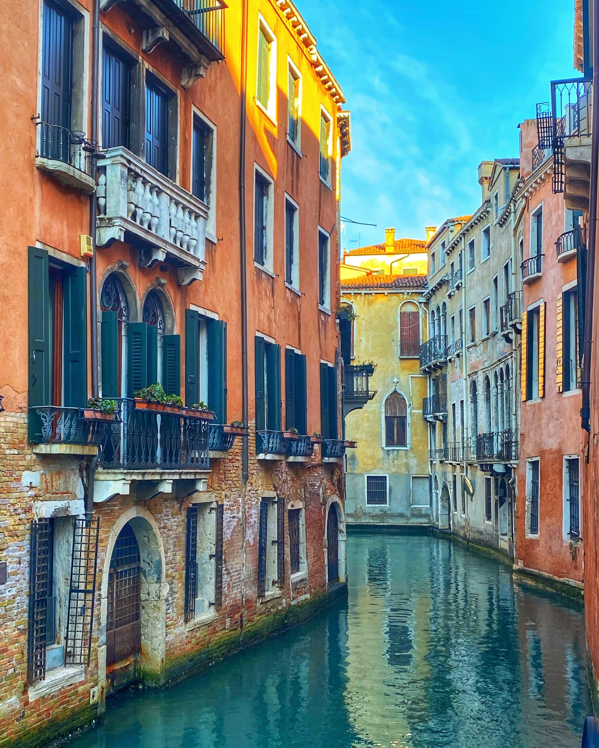 Vista de los edificios históricos a orillas del canal de Venecia, con reflejos en el agua y la típica atmósfera veneciana.