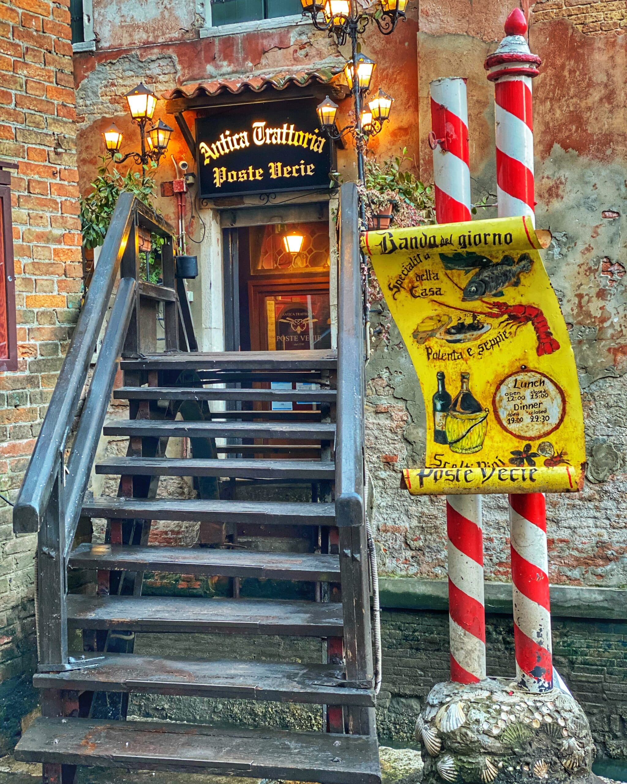Entrada de un restaurante en Venecia, mostrando la fachada típica veneciana y su ambiente acogedor en la calle.