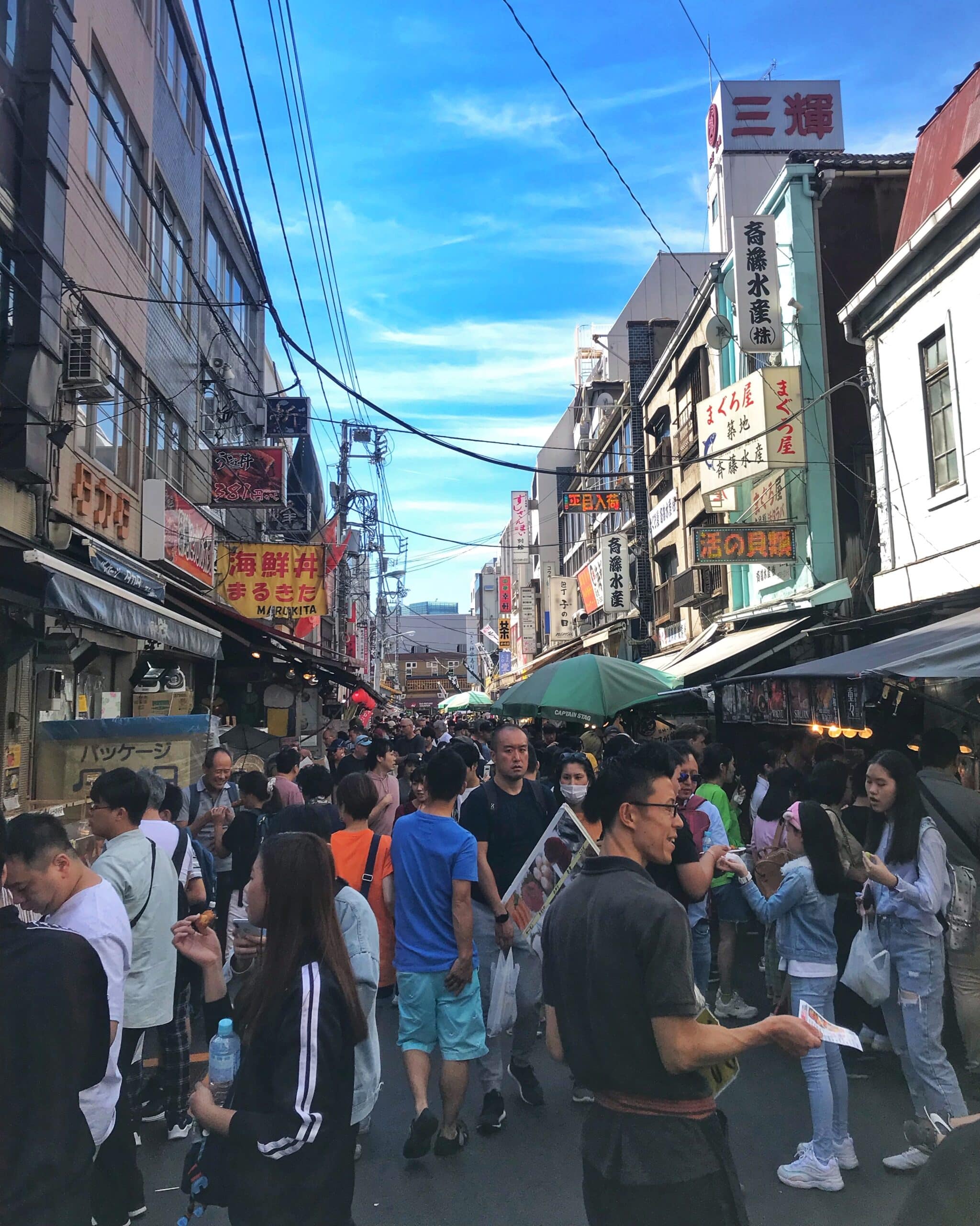 Calle abarrotada de personas durante el día en Tokio con turistas y locales, caminando entre tiendas y edificios, mostrando el bullicio urbano japonés