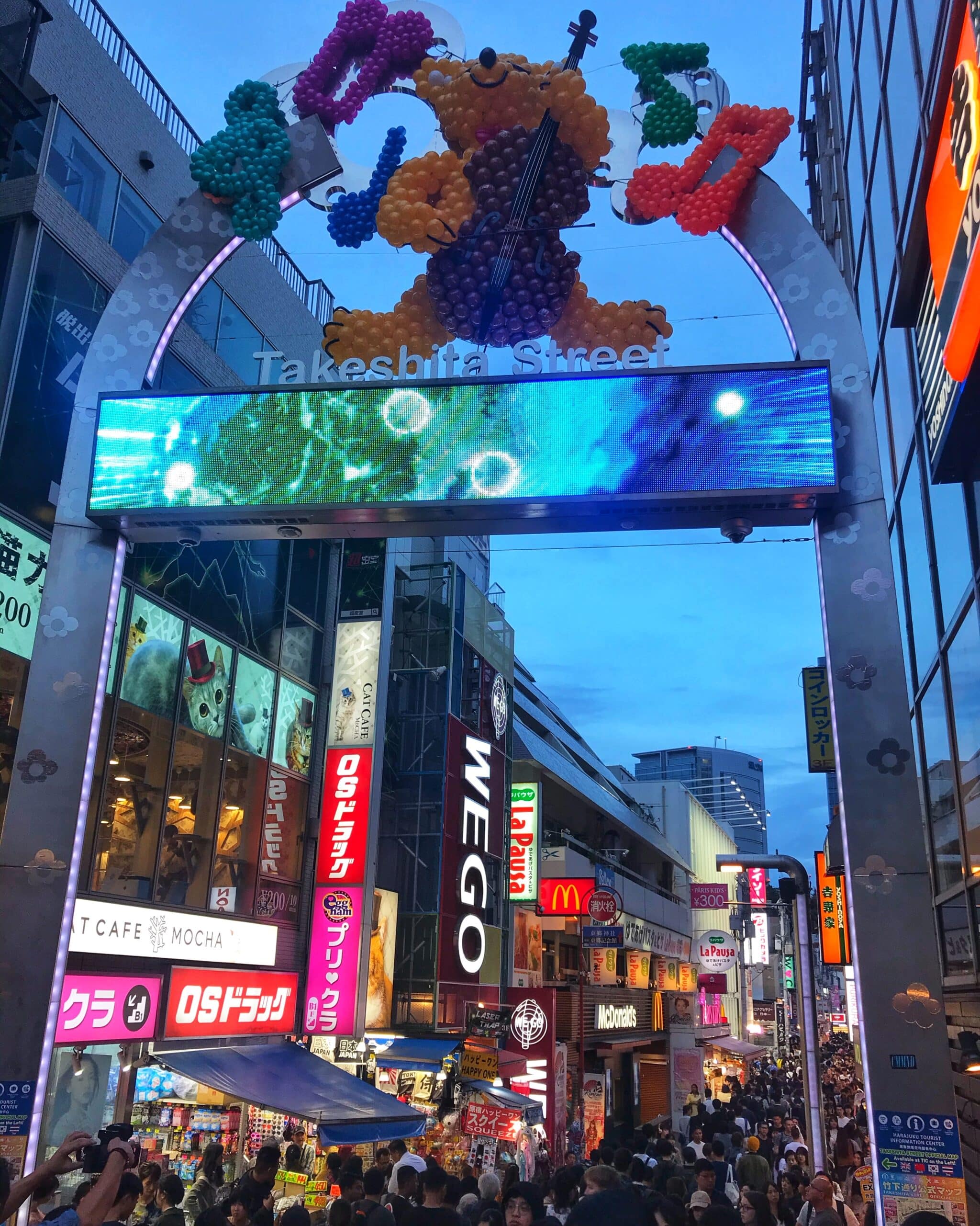 Vista de Takeshita Street en Tokio con multitud de personas caminando entre edificios comerciales y coloridos carteles