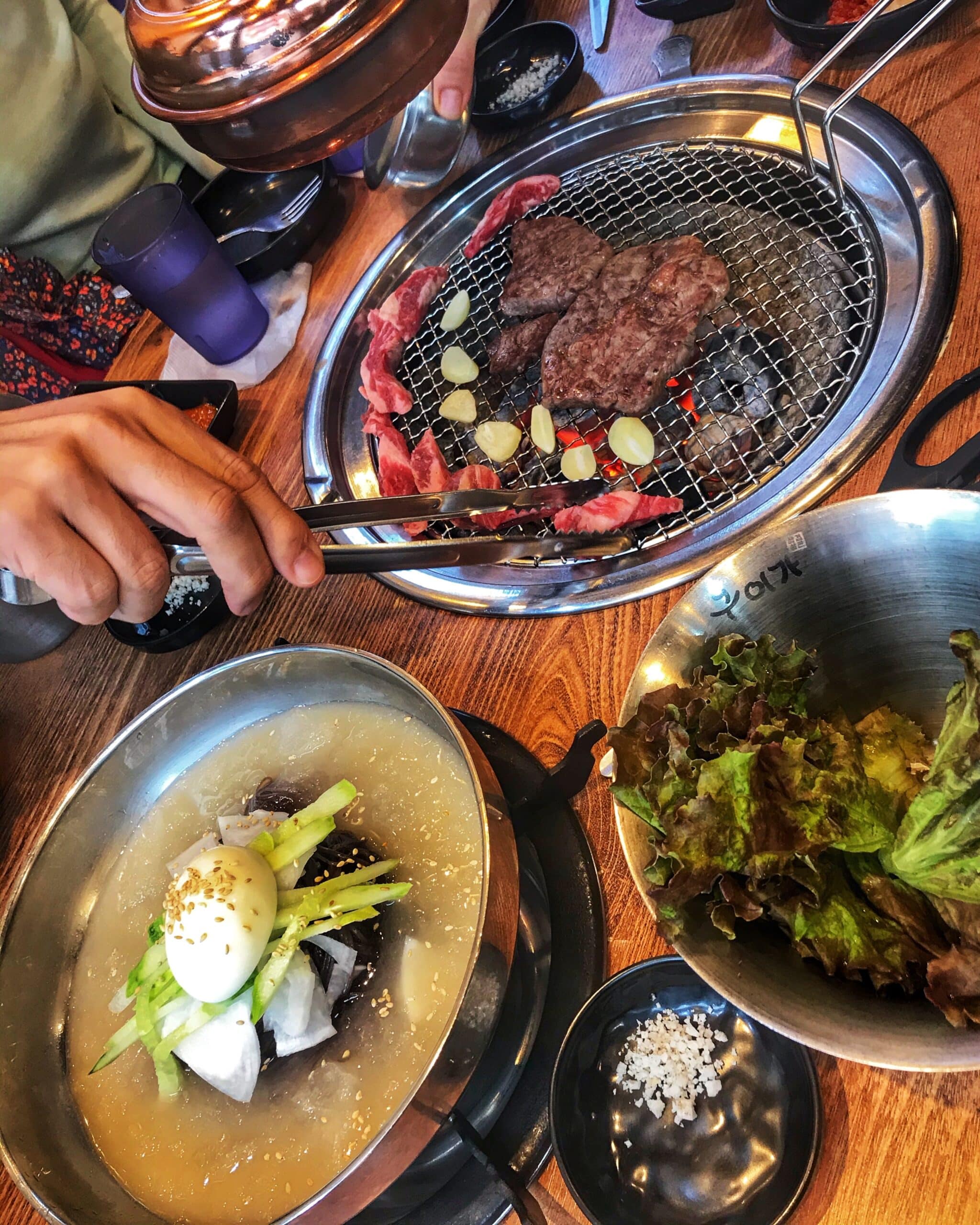 Mesa con barbacoa típica coreana en un restaurante de Seúl con carnes, verduras y utensilios preparados para cocinar, mostrando gastronomía, coreana auténtica