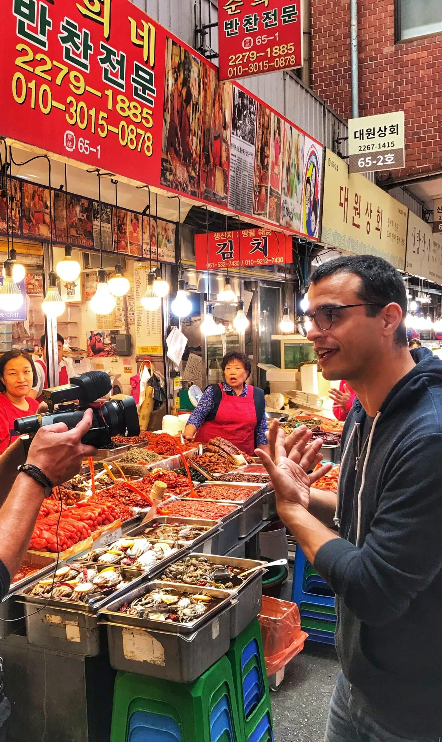 Joven, siendo grabado en un mercado de Seúl mostrando la gastronomía típica y la actividad del mercado coreano