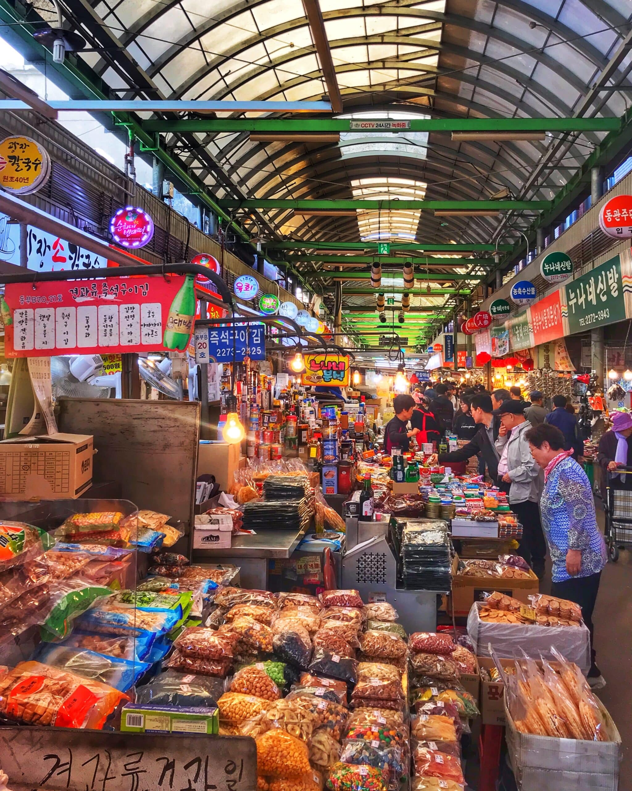 Puestos de comida en un mercado de Seúl, con variedad de alimentos frescos y típicos coreanos, mostrando ambiente animado y concurrido de mercado urbano