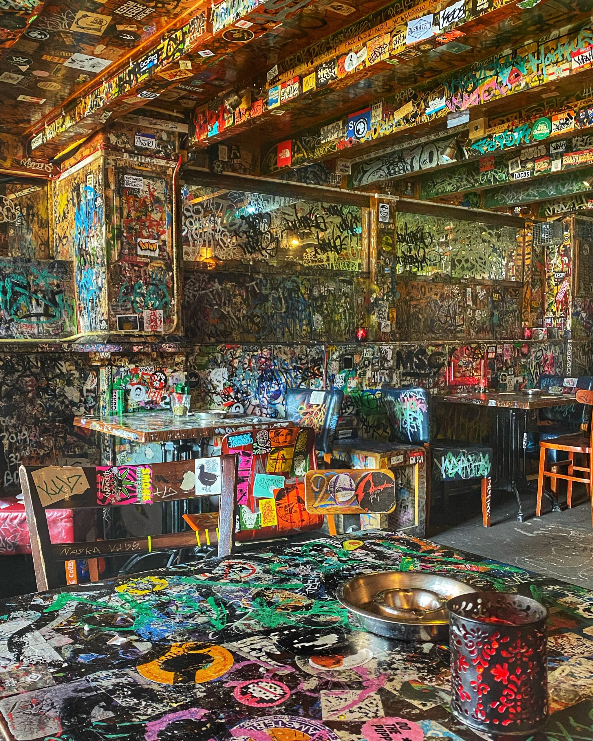 Interior de una cafetería en Ámsterdam con paredes, cubiertas de graffitis, coloridos y ambiente alternativo