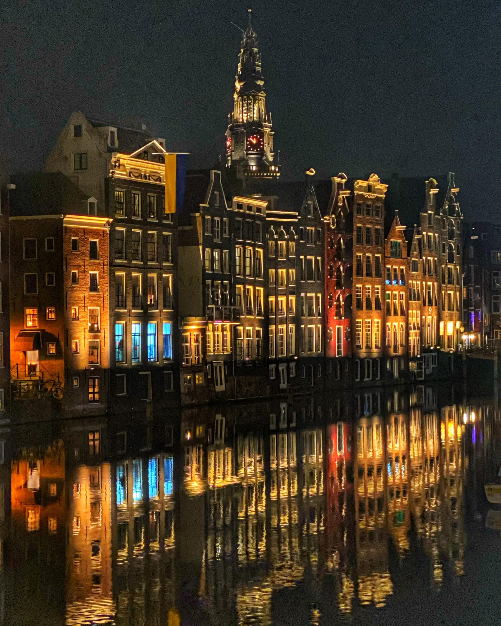 Calle de Ámsterdam con edificios iluminados durante la noche